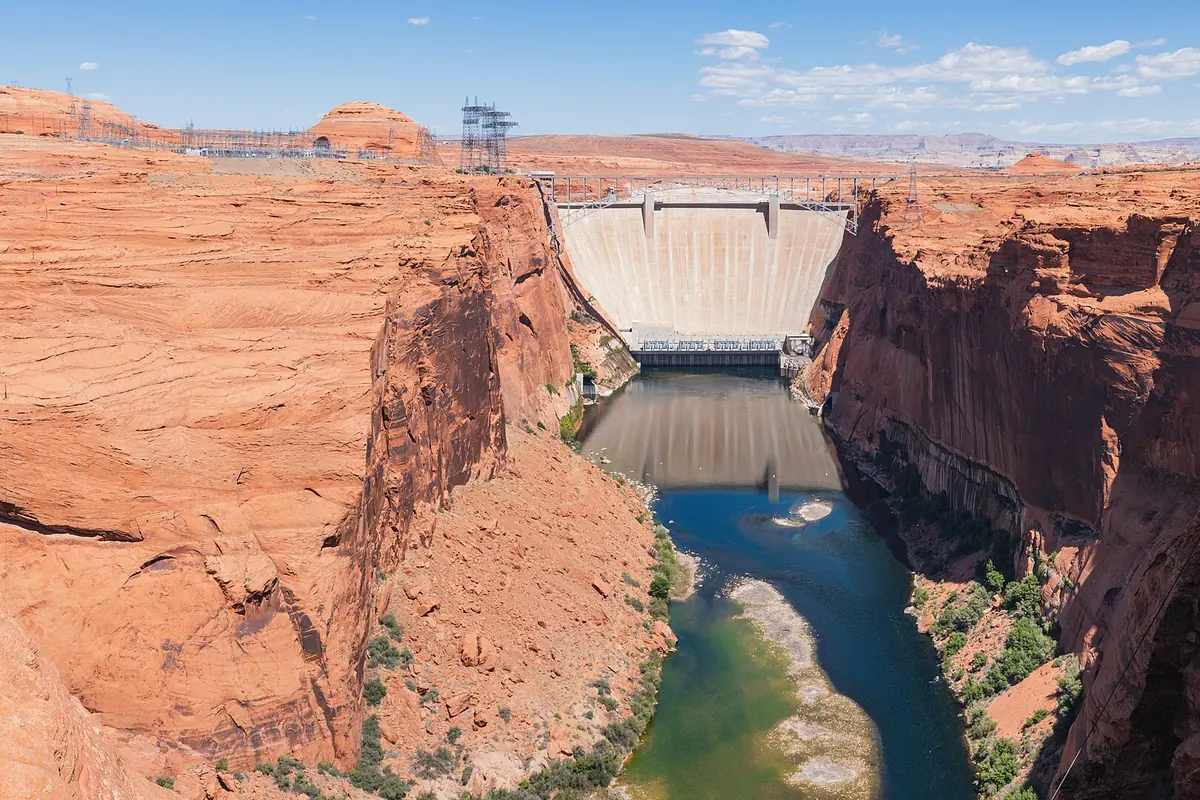 Glen Canyon Dam from downstream, with the Colorado River below the red cliffs.