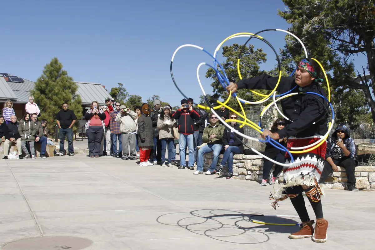A hoop dancer spinning a cluster of coloured hoops while visitors watch, photographed at Grand Canyon National Park.