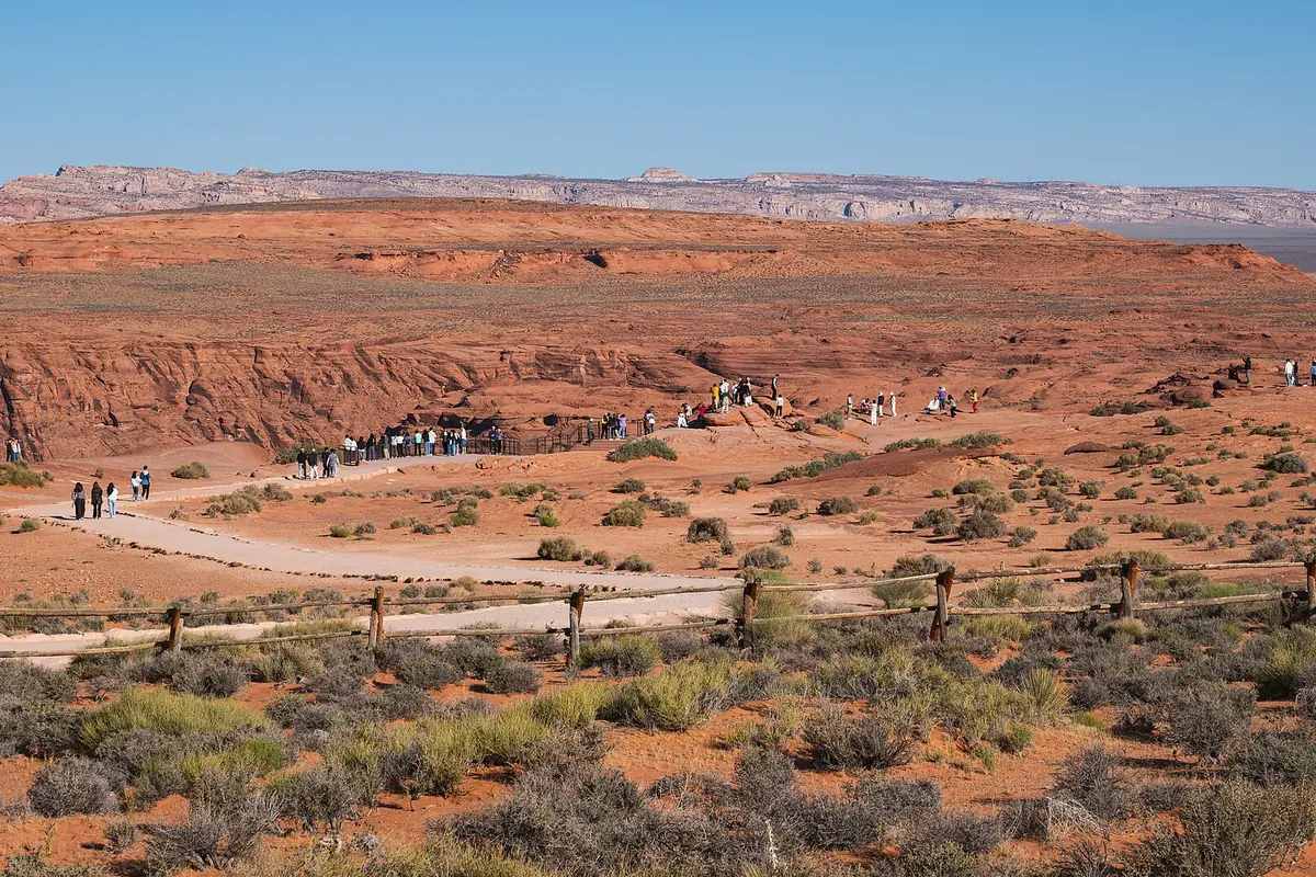 The approach to the Horseshoe Bend overlook, with visitors on the red plateau.