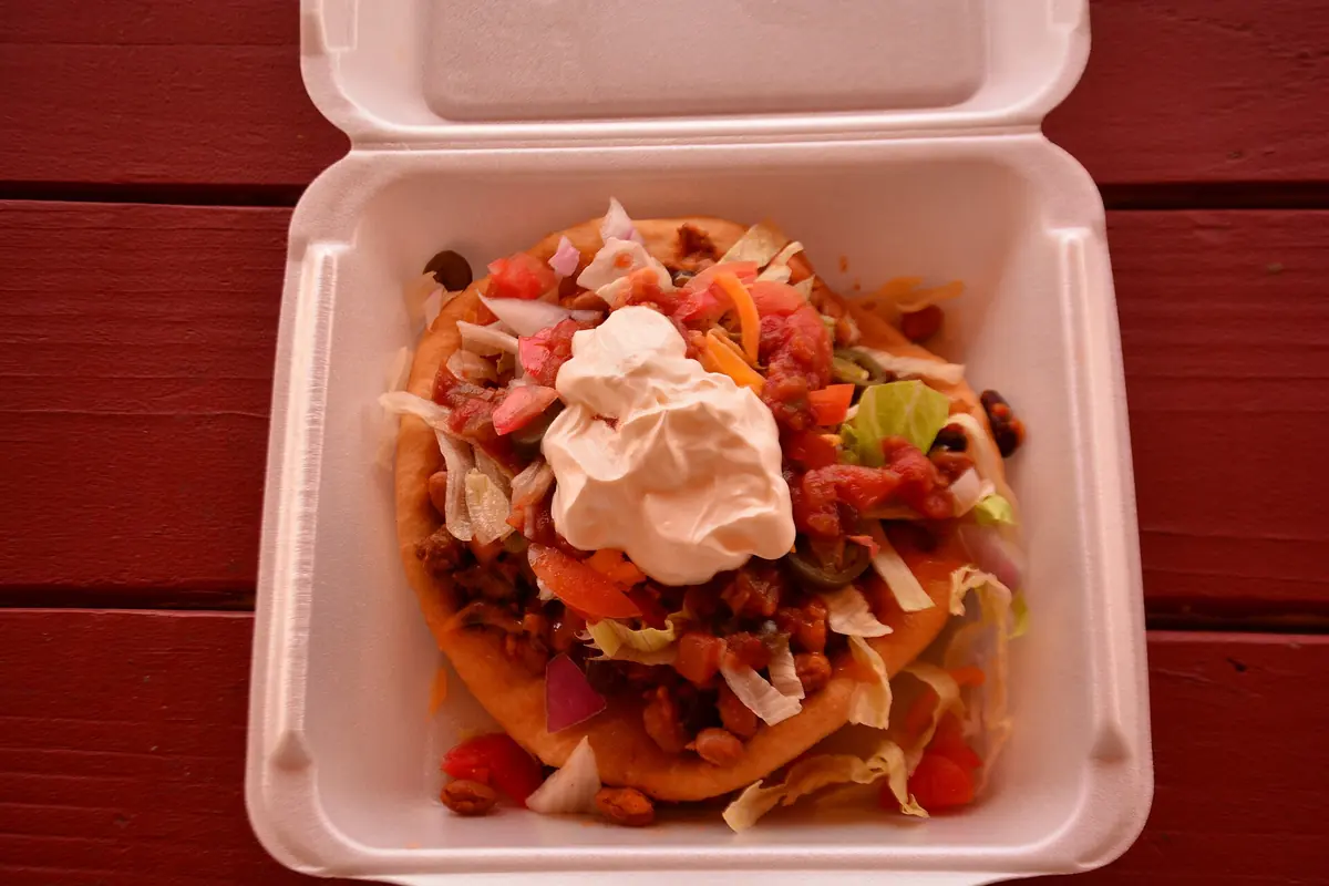A Navajo taco on fry bread with lettuce, tomato, beans and sour cream, photographed at another restaurant.